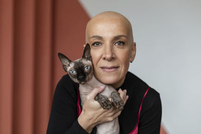 Bald woman embracing hairless sphynx cat