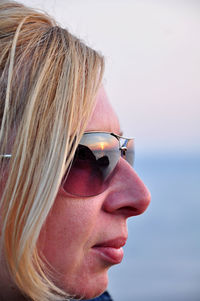 Close-up portrait of woman wearing sunglasses against sky
