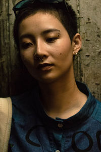 Close-up of young woman standing against wall