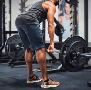 Low section of young man lifting dumbbell in gym