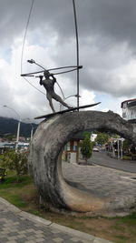 Statue by street against sky in city