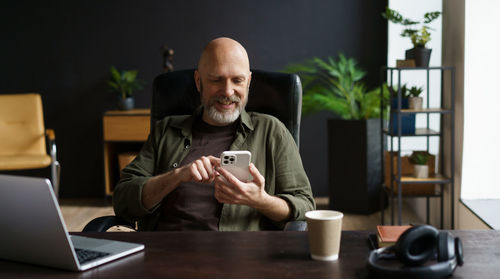 Young woman using mobile phone while sitting on table