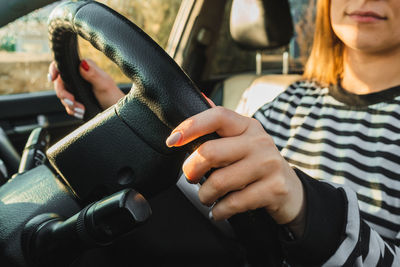 Female hands on black steering wheel of modern car. automobile saloon. woman driving on road. 