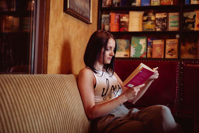 Young woman reading book on sofa