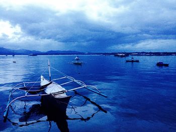 Boats in sea against cloudy sky