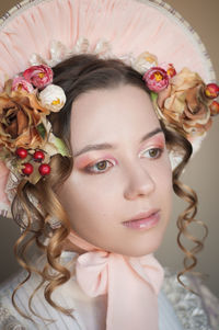 Close-up of beautiful young woman wearing flowers and hat
