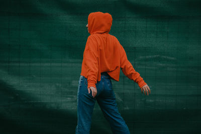 Rear view of person standing against orange wall