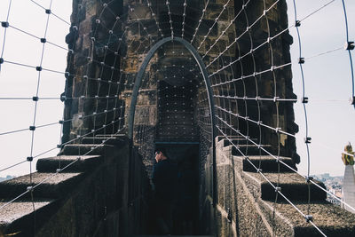 Low angle view of man standing on building against sky