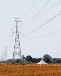 Low angle view of electricity pylon on field against clear sky