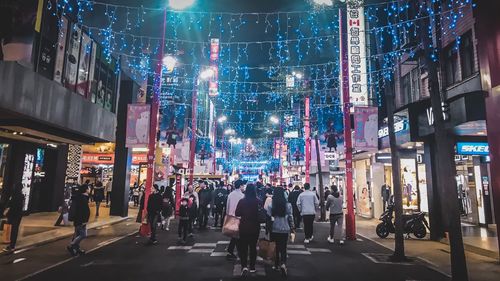 People walking on illuminated street at night