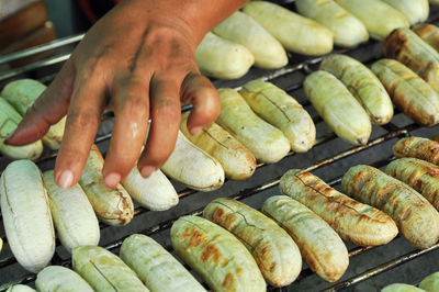 Close-up of person preparing meat on barbecue grill