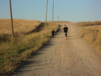 Rear view of man walking on dirt road