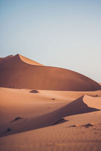 Sand dunes in desert against clear sky