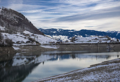 Scenic view of lake by snowcapped mountains against sky