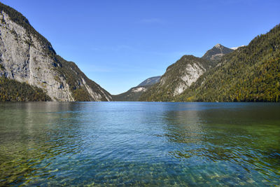 Scenic view of lake and mountains against clear blue sky