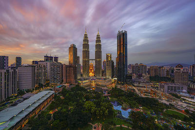 Illuminated city against cloudy sky