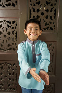 Portrait of smiling boy standing against door