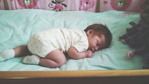 High angle view of toddler sleeping in crib