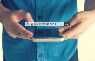 Midsection of man searching e-government on mobile phone