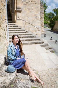 Attractive young woman sitting and posing on ancient stone stairs outdoor