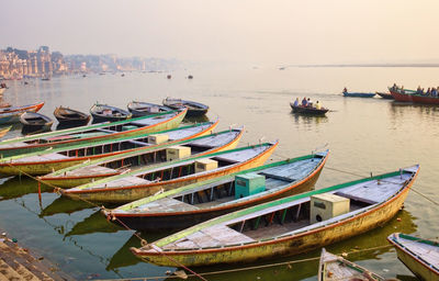 Bunch of old wooden colorful boats docked in the bay of ganges river bank during sunset sunrise