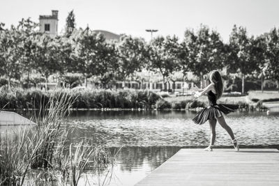 Woman ballet dancing on pier over lake against sky