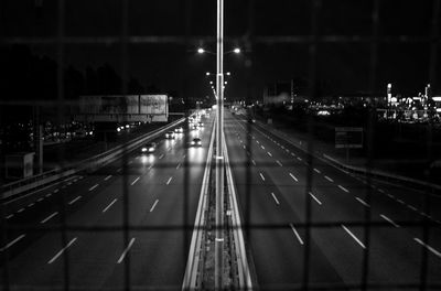 Vehicles on highway at night seen from metal grate