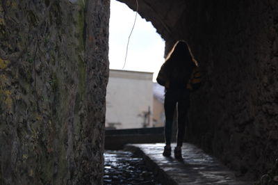 Rear view of woman walking on tunnel