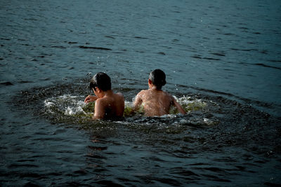 Rear view of shirtless man swimming in sea