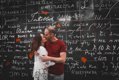 Couple kissing against blackboard with text