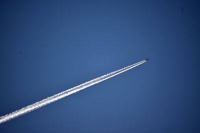 Low angle view of airplane flying against clear blue sky