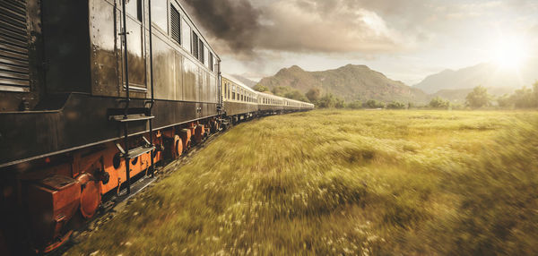 Train moving on railroad track against cloudy sky