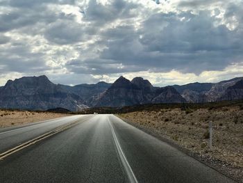 Road by mountains against sky