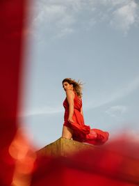 Low angle view of woman looking away on terrace against sky