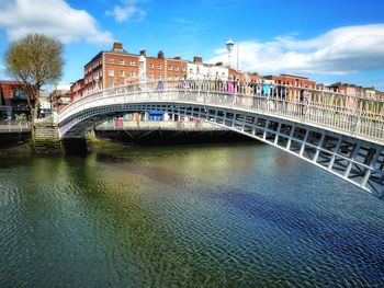 People on hapenny bridge over river in city