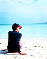 Rear view of woman sitting on beach