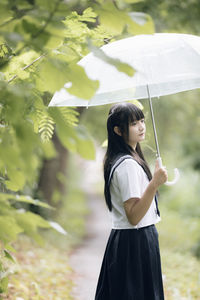 Young student with umbrella standing in park