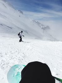 Man snowboarding on snow covered field against sky