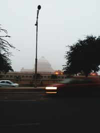 Cars on street in city against clear sky