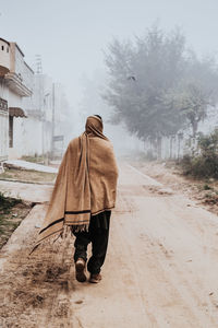 Rear view of woman walking on dirt road