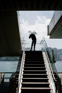 Full length of man standing on railing against sea