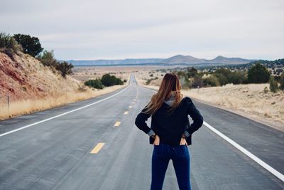 Woman standing on road against sky