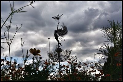 Low angle view of trees against cloudy sky