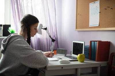 A student is sitting at her desk doing schoolwork.