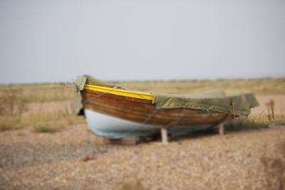 Close-up of boat on field against clear sky