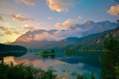 Scenic view of lake and mountains against sky at sunset