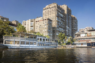 Tower blocks on the banks of the river nile, with a boat in the foreground, cairo, egypt