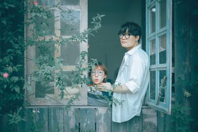 Young couple standing against plants