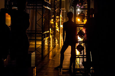 Silhouette of man standing in illuminated room