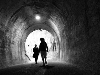 Silhouette of people walking in tunnel